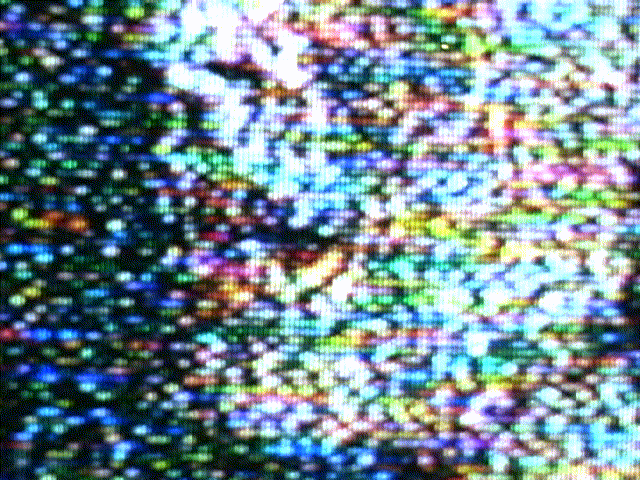 From a prior era: a camera pointed at a CRT in the closing days of analogue TV broadcast. Two cuts of highly zoomed faces, cropped below the eyes, likely from a telenovela. The loop repeats at a cascading horizontal artifact from previously recorded footage on the original MiniDV tape.